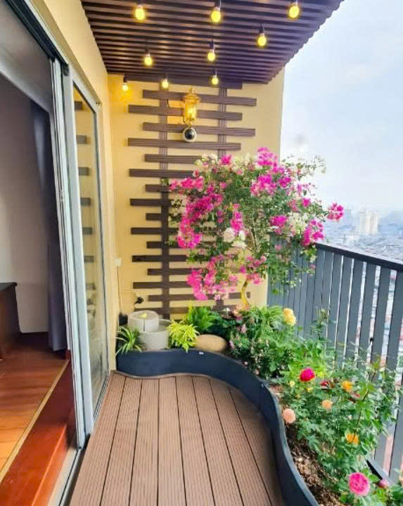 Ban công chung cư hẹp với sàn gỗ nhựa, tường lam gỗ và giàn hoa giấy
